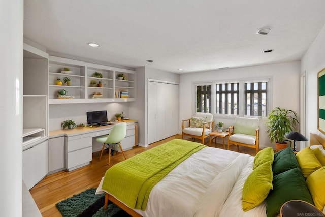 bedroom with built in desk, light hardwood / wood-style floors, and a closet