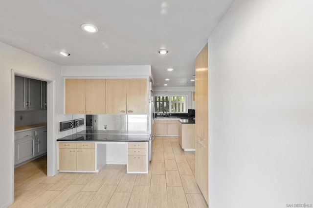 kitchen featuring light brown cabinetry, sink, and stainless steel fridge