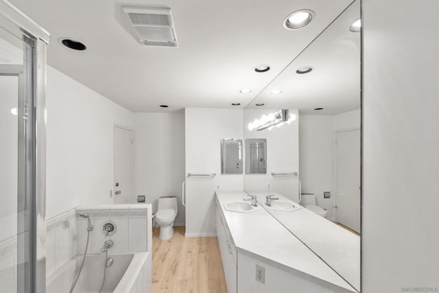 bathroom with hardwood / wood-style flooring, vanity, toilet, and a bathtub