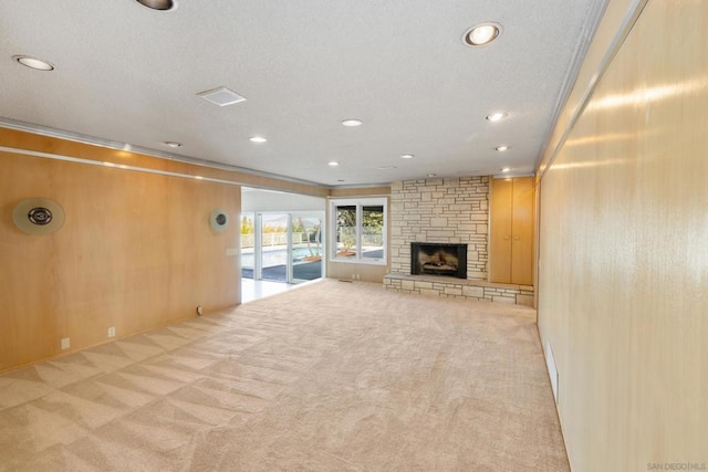 unfurnished living room featuring light colored carpet, a fireplace, and wood walls