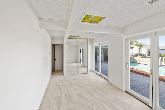 carpeted spare room with beamed ceiling and a textured ceiling