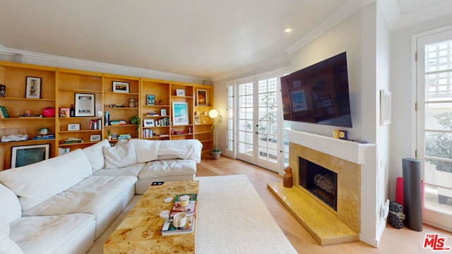 living room with crown molding, a high end fireplace, light hardwood / wood-style floors, and french doors