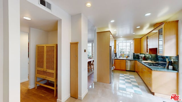 kitchen with appliances with stainless steel finishes, stone countertops, and decorative backsplash