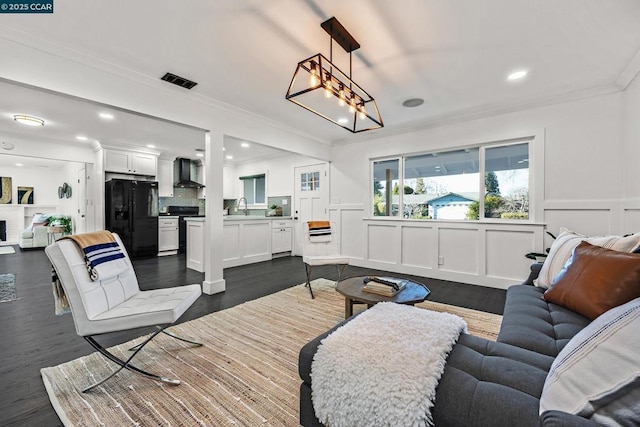 living room featuring crown molding, a fireplace, dark hardwood / wood-style floors, and sink