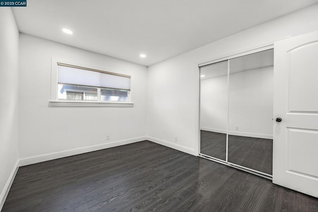 unfurnished bedroom with dark wood-type flooring and a closet