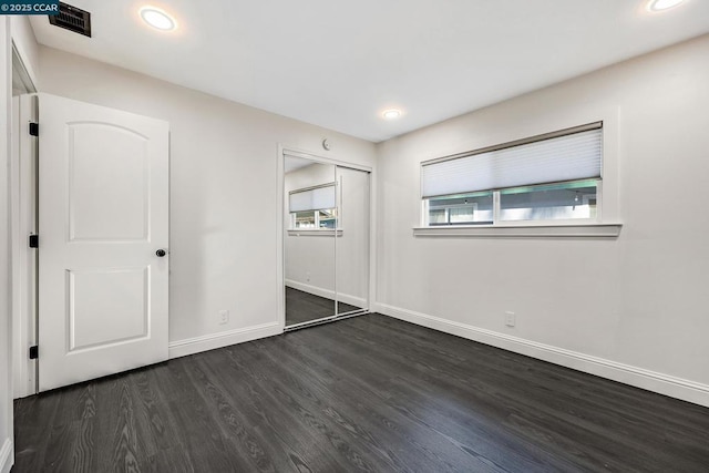 unfurnished bedroom featuring dark wood-type flooring and a closet