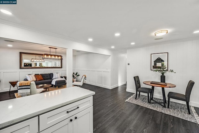 kitchen with pendant lighting, light stone counters, white cabinetry, and dark wood-type flooring