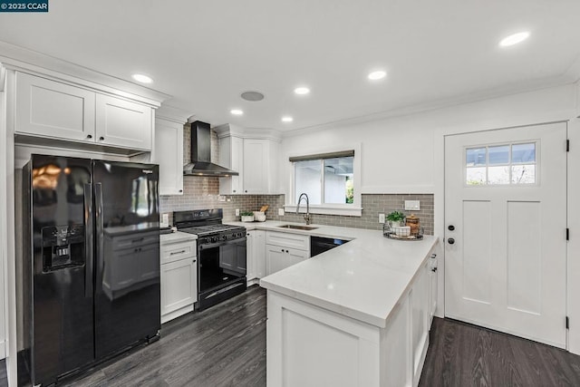 kitchen with sink, wall chimney range hood, white cabinets, and black appliances