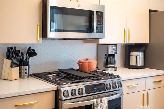 kitchen with light stone counters, stainless steel appliances, and tasteful backsplash