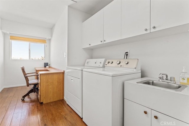 clothes washing area with baseboards, cabinet space, a sink, light wood-style floors, and independent washer and dryer