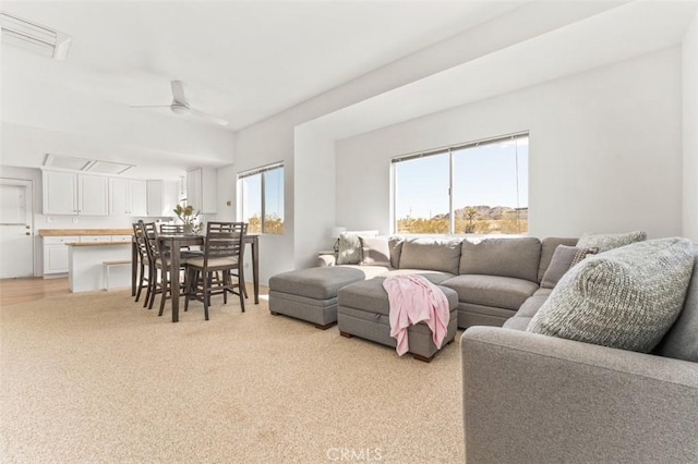 living room featuring a ceiling fan, light colored carpet, and a wealth of natural light