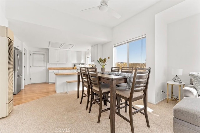 dining space with light carpet and ceiling fan