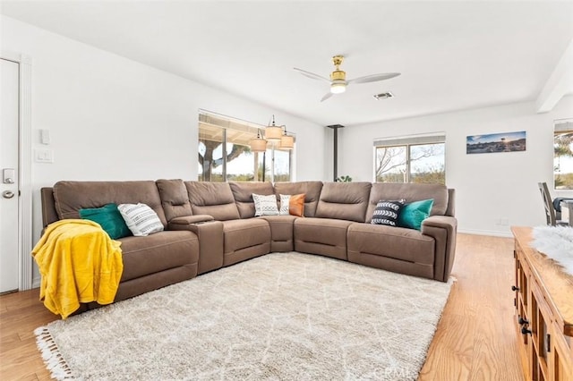 living area with visible vents, baseboards, wood finished floors, and a ceiling fan