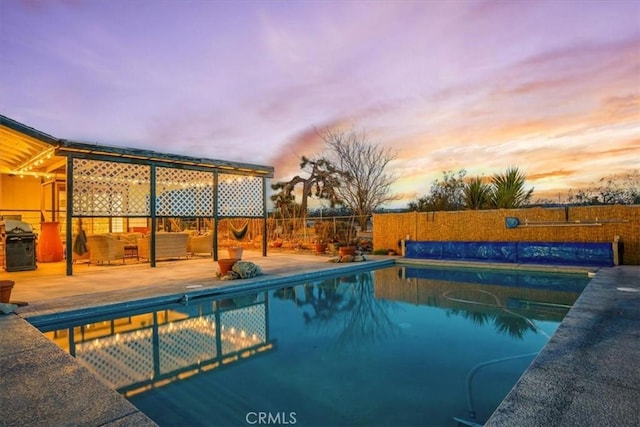 pool at dusk featuring a patio area, a fenced in pool, and fence