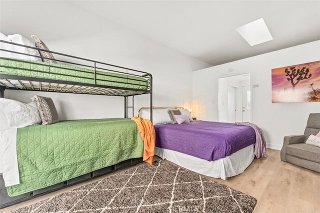 bedroom with a skylight, baseboards, and wood finished floors