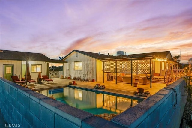 pool at dusk featuring central AC unit, fence, a patio area, and an outdoor pool