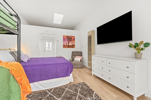 bedroom featuring lofted ceiling with skylight, light hardwood / wood-style flooring, and a closet