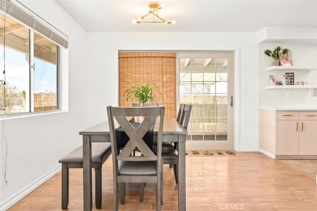 dining room with a notable chandelier, light wood-style flooring, and baseboards