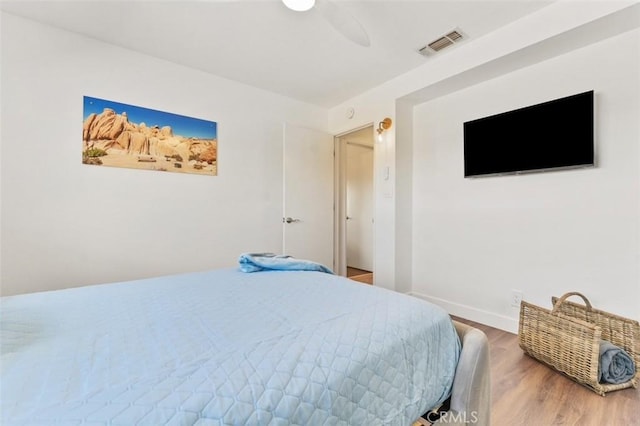 bedroom featuring visible vents, baseboards, wood finished floors, and a ceiling fan