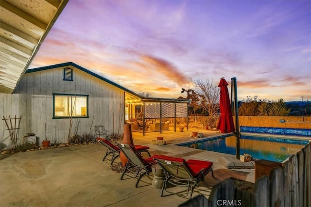 patio terrace at dusk with a fenced in pool