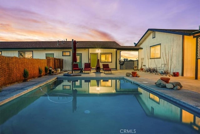 pool at dusk with a patio area