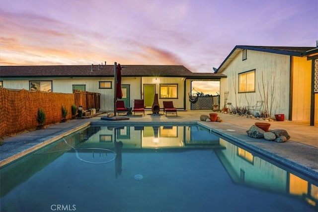 back of house at dusk featuring a fenced in pool, a patio, and fence