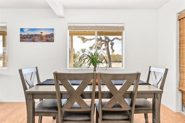 dining space with beamed ceiling and light hardwood / wood-style flooring