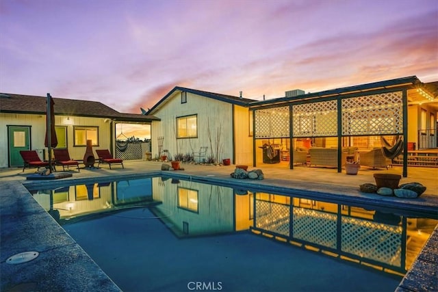 pool at dusk featuring an outdoor pool and a patio area