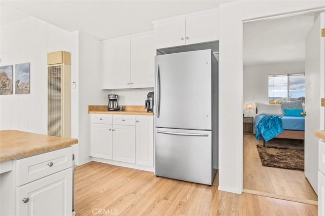 kitchen with white cabinetry, butcher block counters, stainless steel fridge, and light wood-type flooring