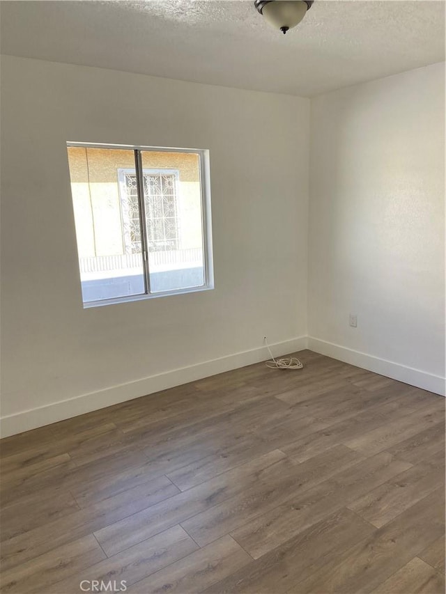 unfurnished room featuring hardwood / wood-style flooring and a textured ceiling