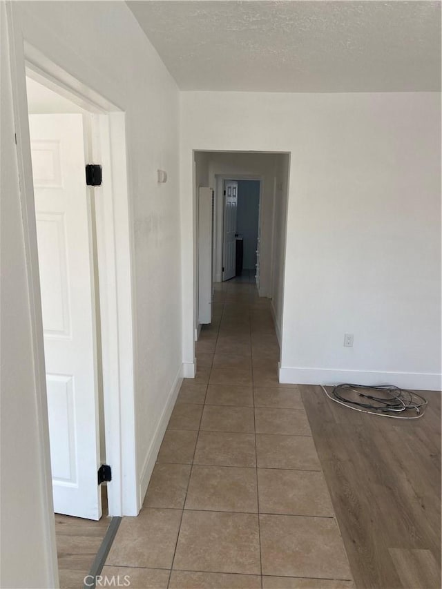 hallway featuring tile patterned flooring and a textured ceiling