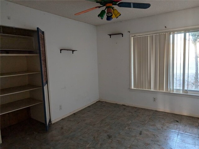 unfurnished room featuring ceiling fan, a wealth of natural light, and a textured ceiling