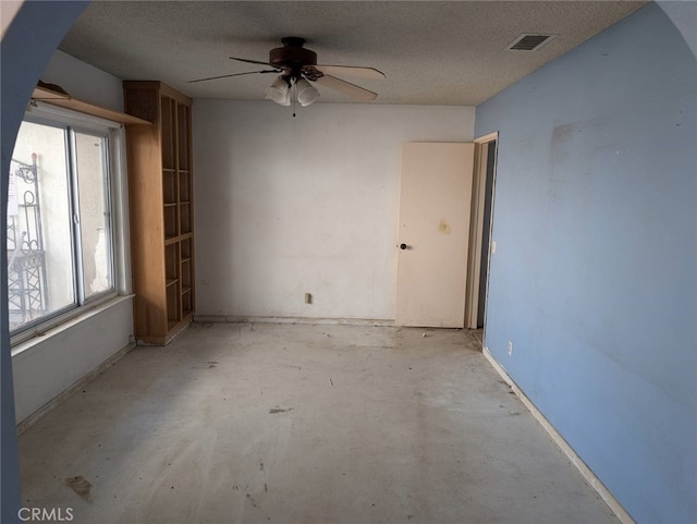 empty room featuring ceiling fan, plenty of natural light, and a textured ceiling