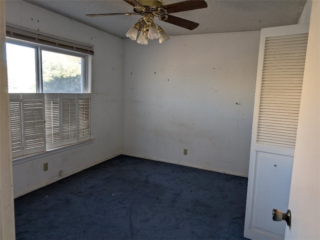 unfurnished room featuring dark colored carpet, ceiling fan, and a textured ceiling