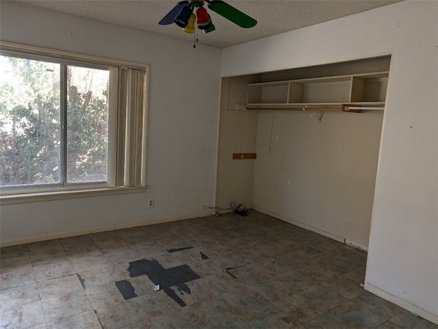 unfurnished bedroom with multiple windows, a textured ceiling, ceiling fan, and a closet