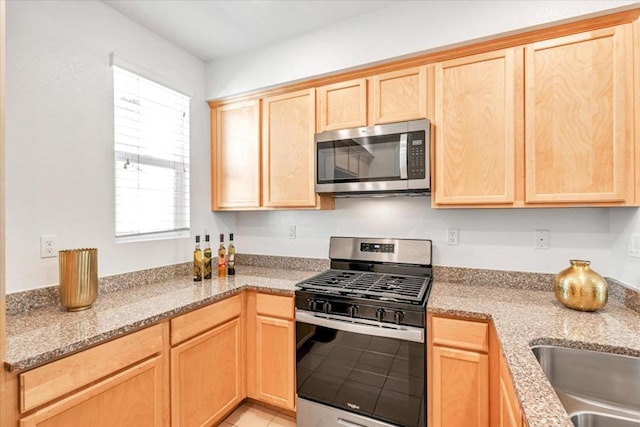 kitchen with light stone counters, appliances with stainless steel finishes, and light brown cabinetry