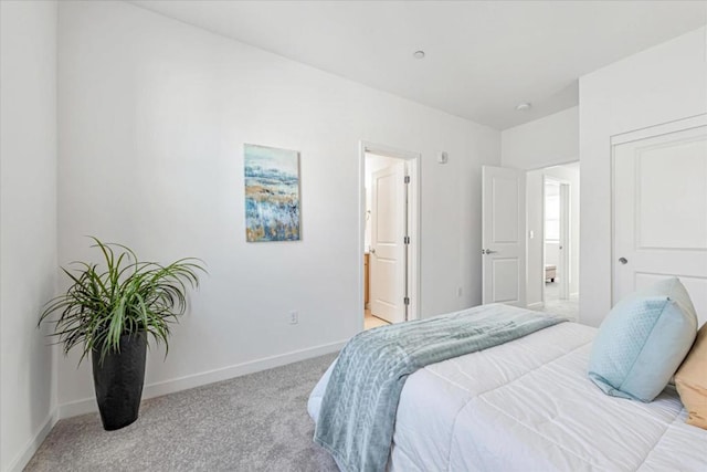 bedroom featuring connected bathroom and light colored carpet