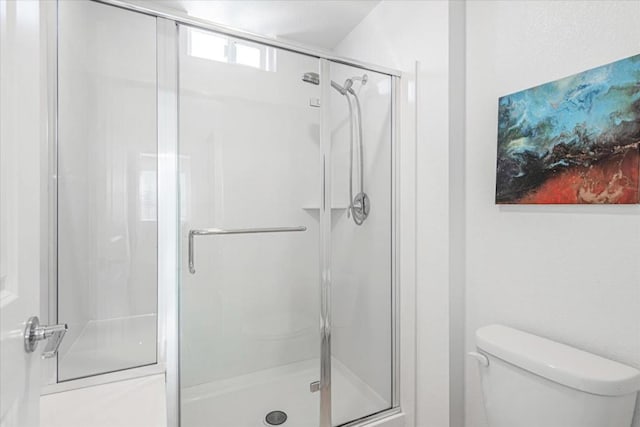 bathroom featuring a shower with shower door and toilet