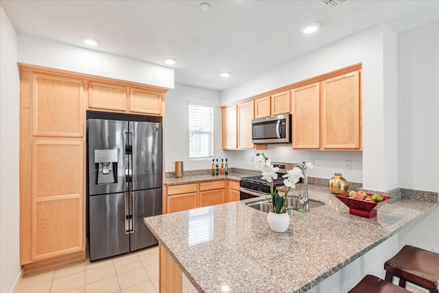 kitchen featuring light stone counters, stainless steel appliances, kitchen peninsula, and light brown cabinets