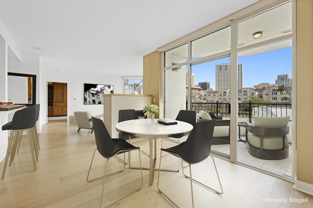 dining space with expansive windows, a city view, and light wood finished floors