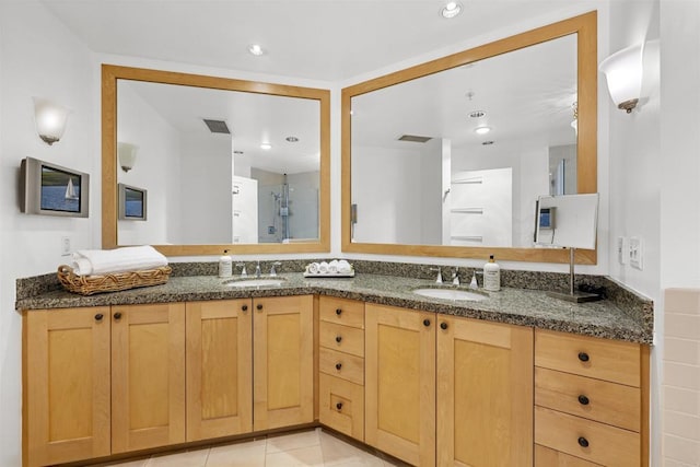 full bathroom with double vanity, a stall shower, a sink, and visible vents