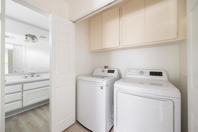 laundry room featuring cabinets, sink, washer and dryer, and light wood-type flooring