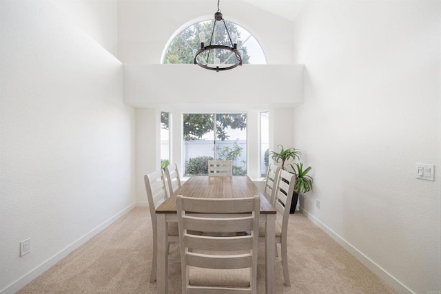 carpeted dining room with a notable chandelier, a wealth of natural light, and high vaulted ceiling