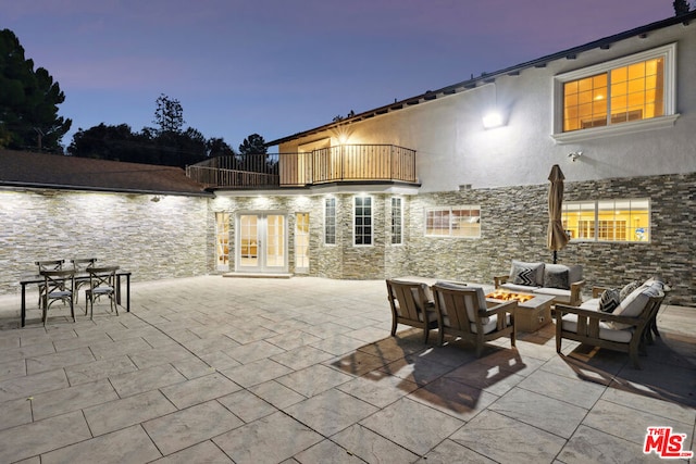 patio terrace at dusk with a fire pit and a balcony