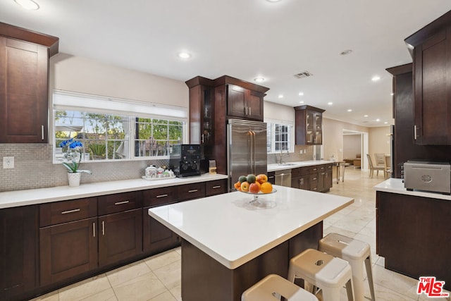 kitchen featuring sink, a breakfast bar area, backsplash, stainless steel appliances, and a kitchen island