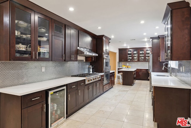 kitchen with tasteful backsplash, sink, beverage cooler, dark brown cabinetry, and stainless steel appliances