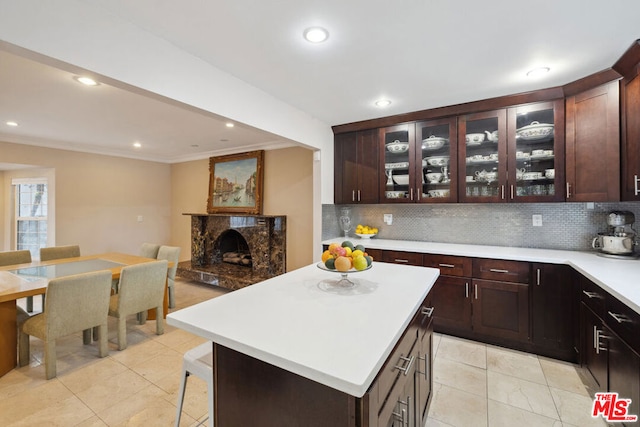 kitchen with crown molding, a center island, a fireplace, and decorative backsplash