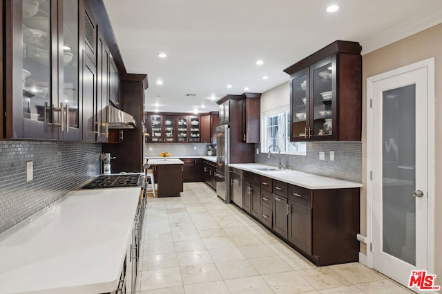 kitchen featuring dark brown cabinetry, sink, a center island, stainless steel appliances, and decorative backsplash