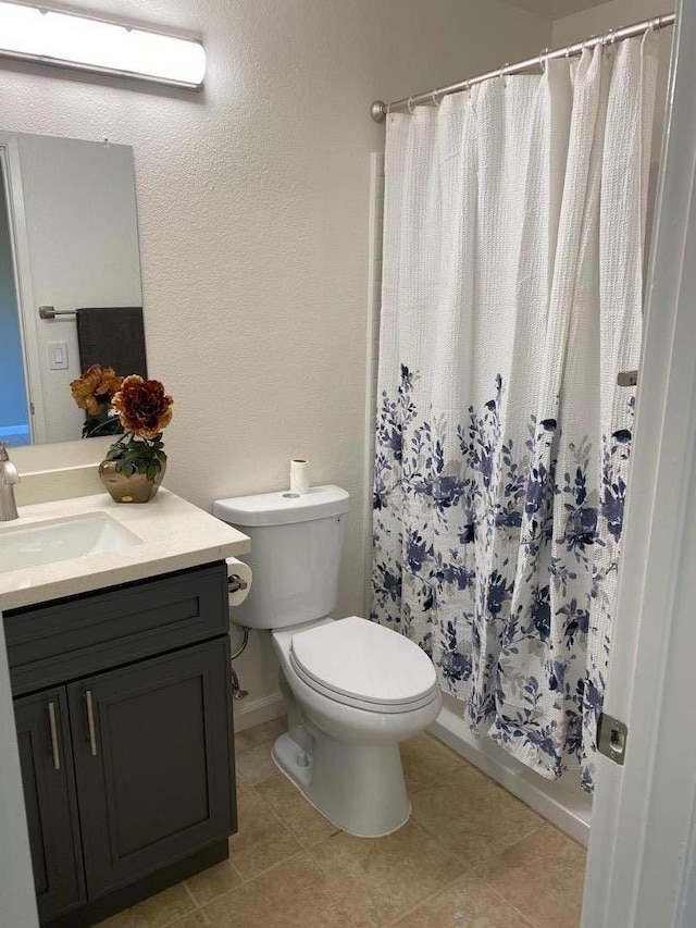 bathroom with vanity, curtained shower, tile patterned floors, and toilet