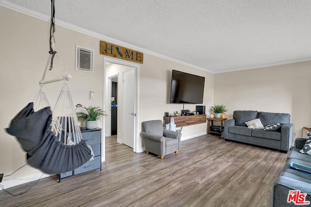 living room with wood-type flooring, ornamental molding, and a textured ceiling